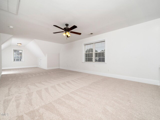 additional living space with visible vents, baseboards, light colored carpet, lofted ceiling, and a ceiling fan