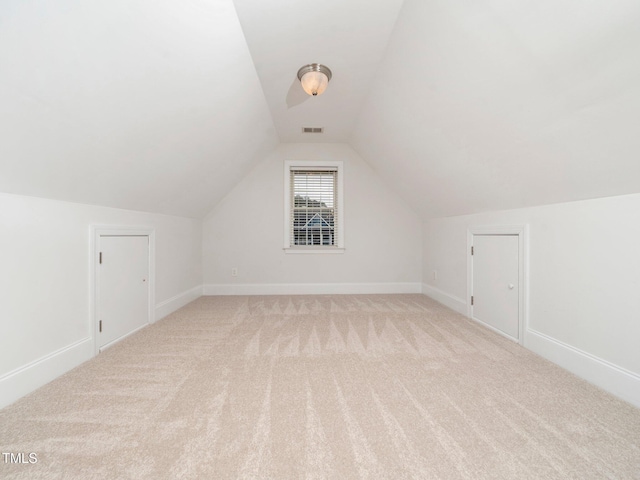 additional living space with visible vents, lofted ceiling, carpet, and baseboards