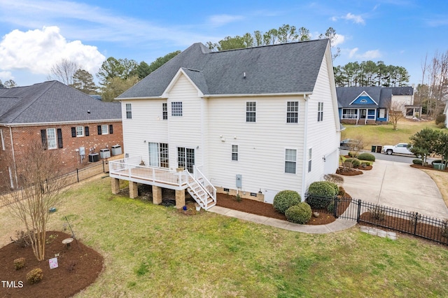 back of house featuring driveway, roof with shingles, a deck, fence private yard, and a lawn