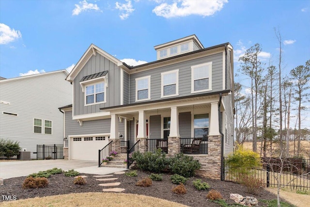 view of front of home featuring driveway, stone siding, fence, covered porch, and board and batten siding