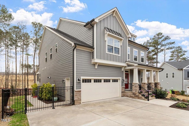 craftsman-style home featuring board and batten siding, fence, concrete driveway, a garage, and stone siding