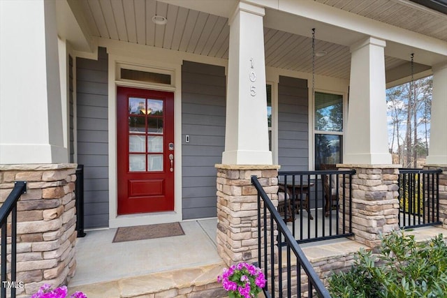 view of exterior entry featuring stone siding and a porch