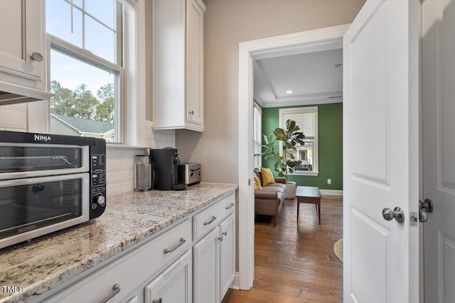 kitchen featuring light wood-type flooring, tasteful backsplash, white cabinetry, recessed lighting, and light stone countertops