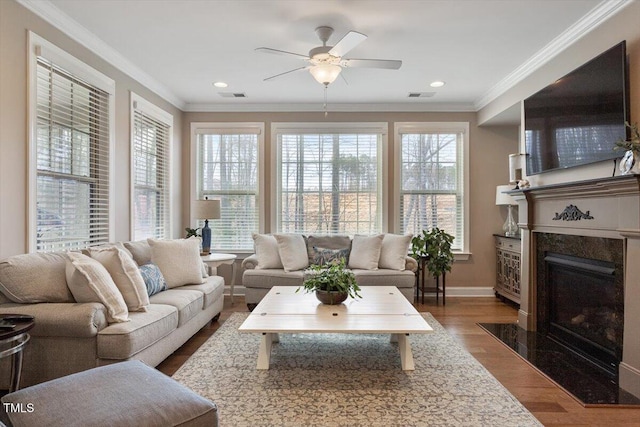 living area featuring visible vents, wood finished floors, a premium fireplace, and crown molding