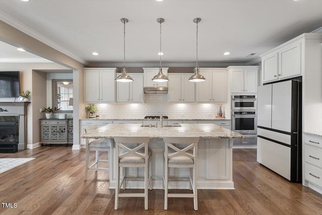 kitchen with a breakfast bar, a sink, backsplash, wood finished floors, and freestanding refrigerator