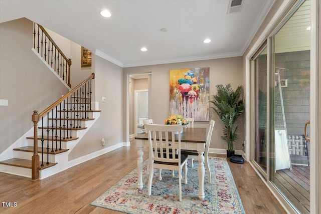 dining space featuring visible vents, ornamental molding, baseboards, and wood finished floors