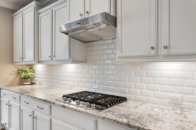 kitchen featuring under cabinet range hood, white cabinets, stainless steel gas cooktop, and tasteful backsplash