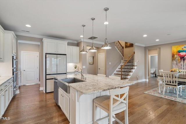 kitchen featuring white cabinets, wood finished floors, crown molding, and a sink