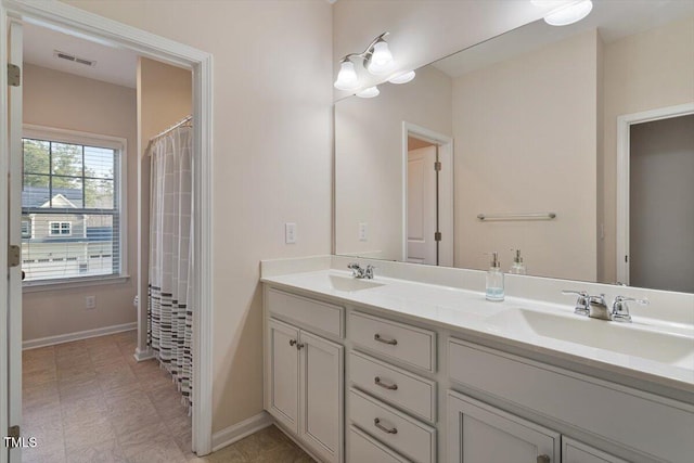 bathroom featuring double vanity, baseboards, visible vents, and a sink