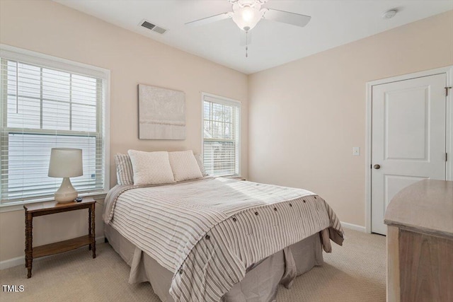 bedroom featuring visible vents, light colored carpet, a ceiling fan, and baseboards