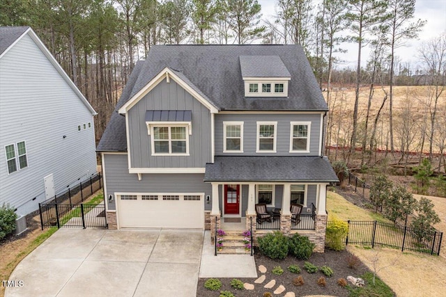 craftsman inspired home with fence, an attached garage, covered porch, concrete driveway, and board and batten siding