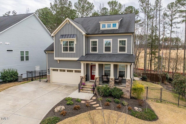 craftsman-style house with fence, driveway, covered porch, a garage, and board and batten siding