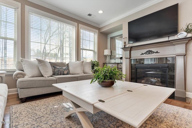 living room featuring visible vents, wood finished floors, a fireplace, crown molding, and baseboards