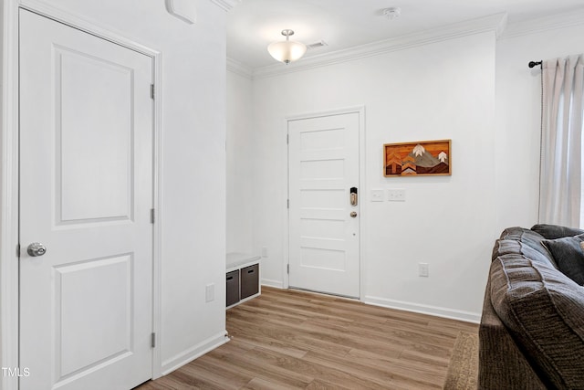 foyer with light wood-type flooring, baseboards, visible vents, and ornamental molding