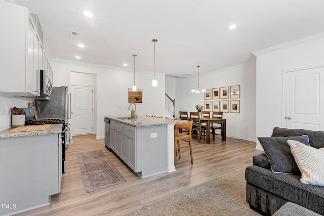 kitchen featuring a breakfast bar, a sink, light wood-style floors, appliances with stainless steel finishes, and open floor plan