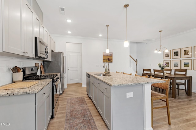 kitchen with light wood-type flooring, a kitchen bar, decorative backsplash, stainless steel appliances, and a sink