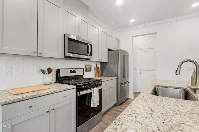 kitchen with a sink, crown molding, tasteful backsplash, and stainless steel appliances