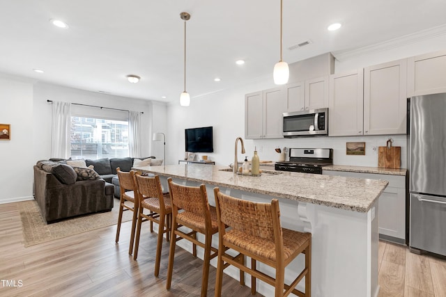 kitchen featuring visible vents, open floor plan, stainless steel appliances, crown molding, and light wood finished floors