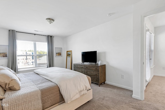 bedroom with light colored carpet and baseboards