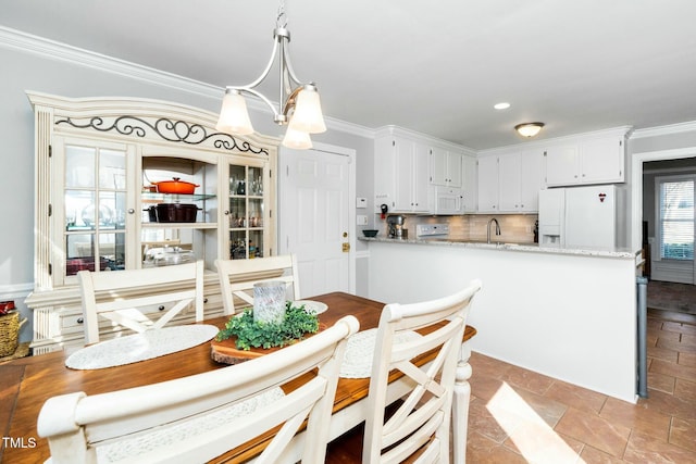 dining space featuring stone finish floor, an inviting chandelier, and ornamental molding