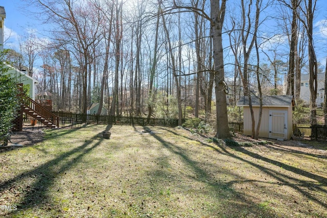 view of yard with a storage shed, an outdoor structure, stairway, and a fenced backyard