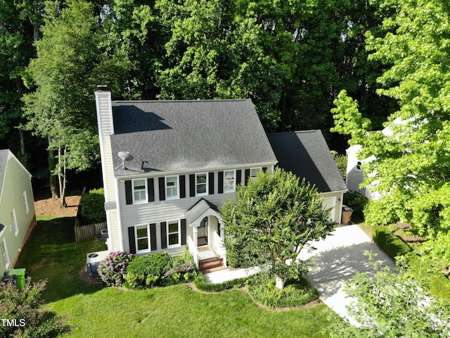 view of front of house featuring a chimney, an attached garage, concrete driveway, and a front yard