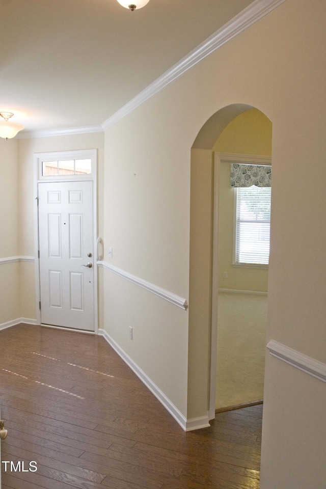 foyer with hardwood / wood-style flooring, baseboards, arched walkways, and ornamental molding