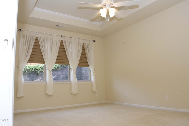 carpeted spare room with a raised ceiling, ornamental molding, a ceiling fan, baseboards, and stairs