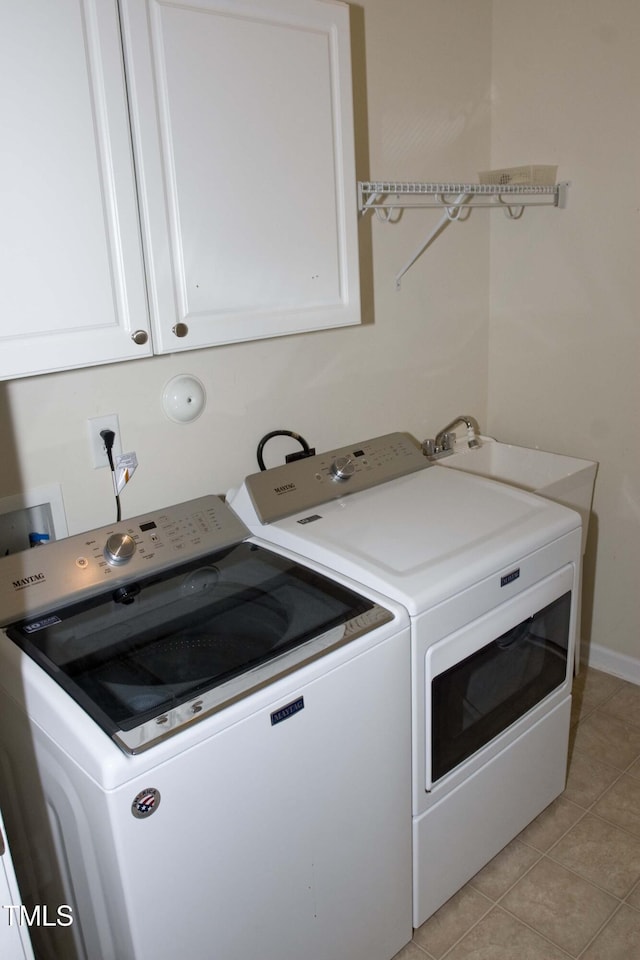 washroom featuring washer and dryer, light tile patterned floors, cabinet space, and a sink