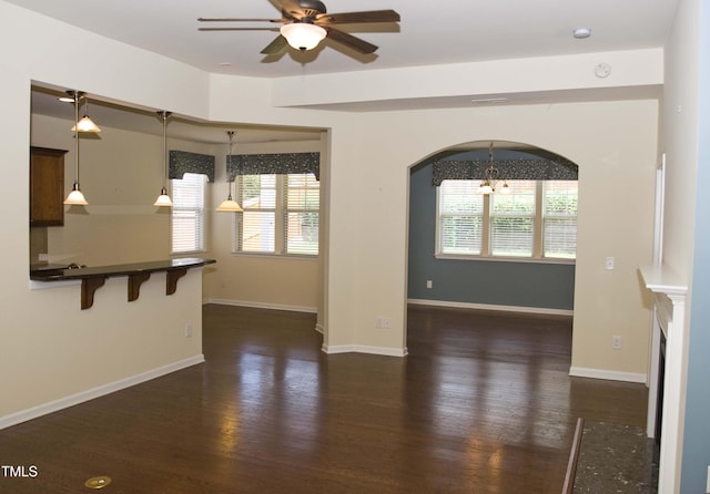 unfurnished living room with baseboards, dark wood-type flooring, and ceiling fan with notable chandelier