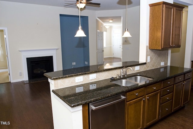 kitchen featuring a fireplace with flush hearth, a sink, tasteful backsplash, stainless steel dishwasher, and dark wood finished floors