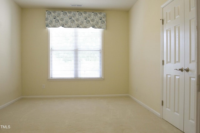 unfurnished room featuring visible vents, baseboards, and light colored carpet