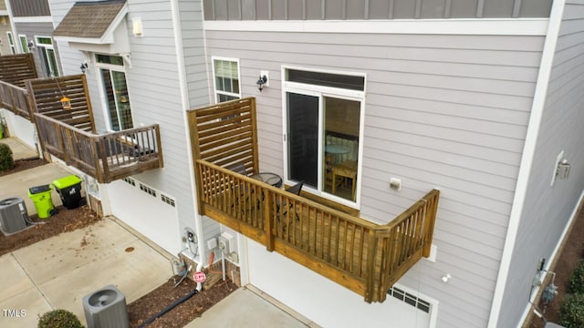 exterior space with central AC unit and roof with shingles