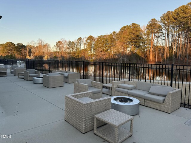 view of patio / terrace featuring a water view, an outdoor living space with a fire pit, and fence