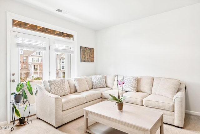 living area with light colored carpet, visible vents, and baseboards