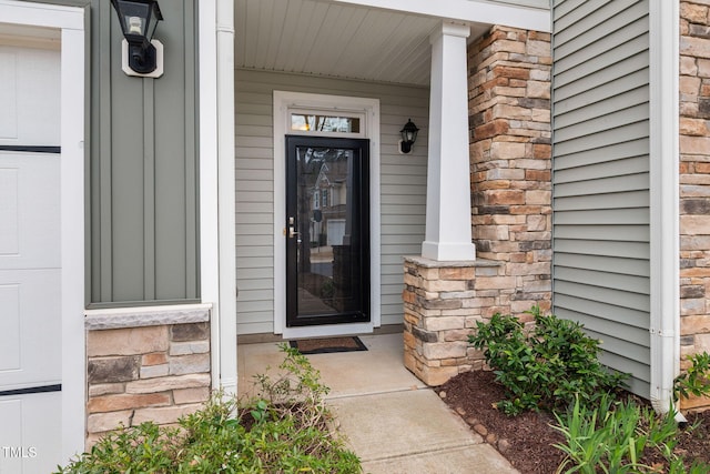 view of exterior entry featuring stone siding and a porch