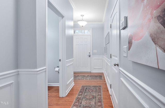 entryway with a decorative wall, wainscoting, crown molding, and wood finished floors