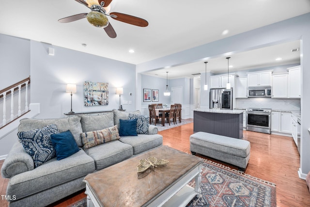 living area featuring stairway, light wood-style flooring, recessed lighting, and a ceiling fan