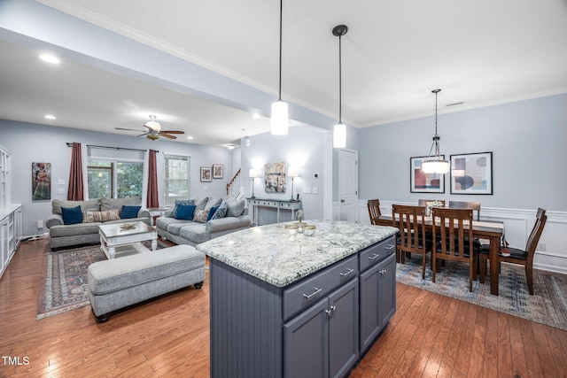 kitchen with hanging light fixtures, crown molding, and wood-type flooring