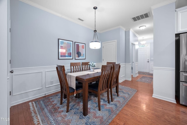 dining area with visible vents, wood-type flooring, and ornamental molding