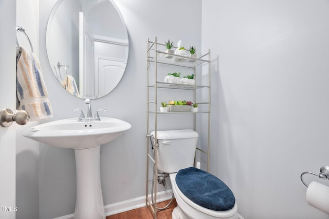 half bathroom featuring toilet, baseboards, and wood finished floors