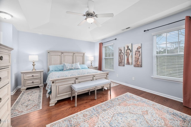 bedroom featuring visible vents, a raised ceiling, dark wood-type flooring, and baseboards