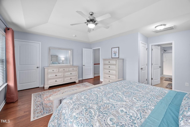 bedroom featuring visible vents, baseboards, a tray ceiling, wood finished floors, and a ceiling fan