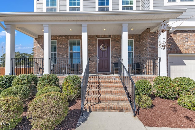 doorway to property featuring a garage, covered porch, and brick siding