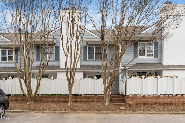 townhome / multi-family property featuring fence and a shingled roof