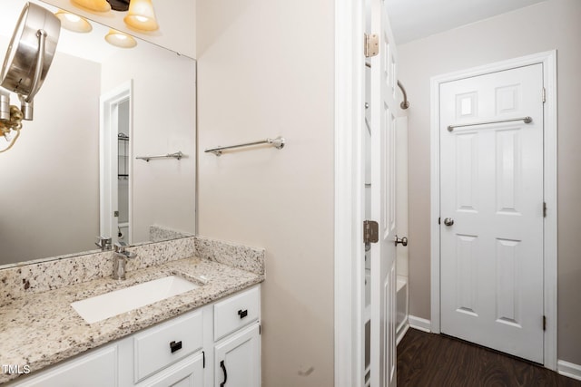 bathroom with a bathing tub, vanity, and wood finished floors