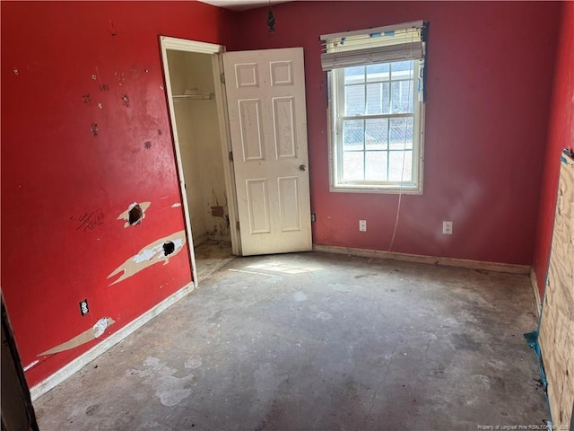 unfurnished bedroom with baseboards and unfinished concrete floors