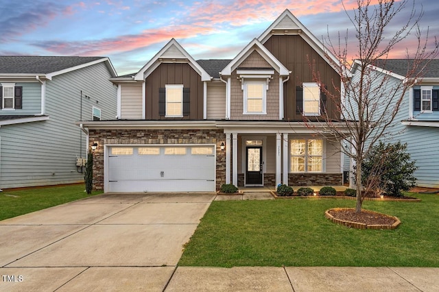 view of front of property featuring an attached garage, a yard, concrete driveway, stone siding, and board and batten siding