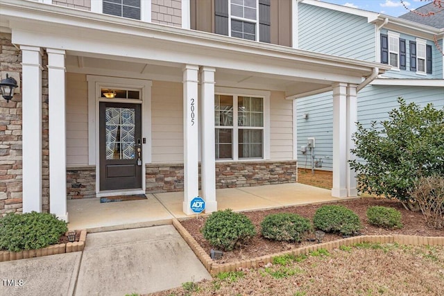 entrance to property featuring stone siding and covered porch