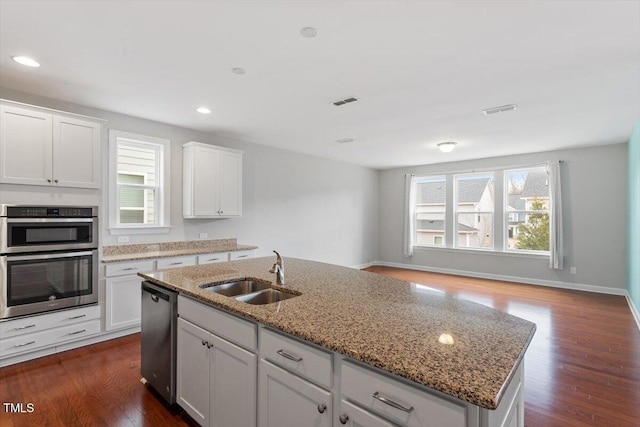 kitchen with visible vents, dark wood-type flooring, stainless steel appliances, white cabinetry, and a sink